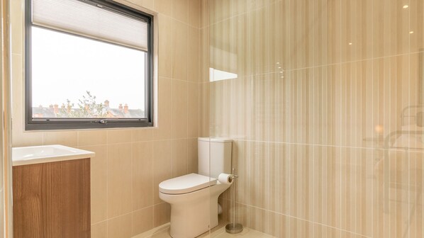 Un baño con inodoro, ventana y zona de ducha.
