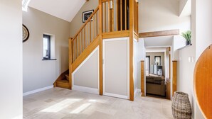 A spacious interior with a wooden staircase, a large window, and a view into another room.