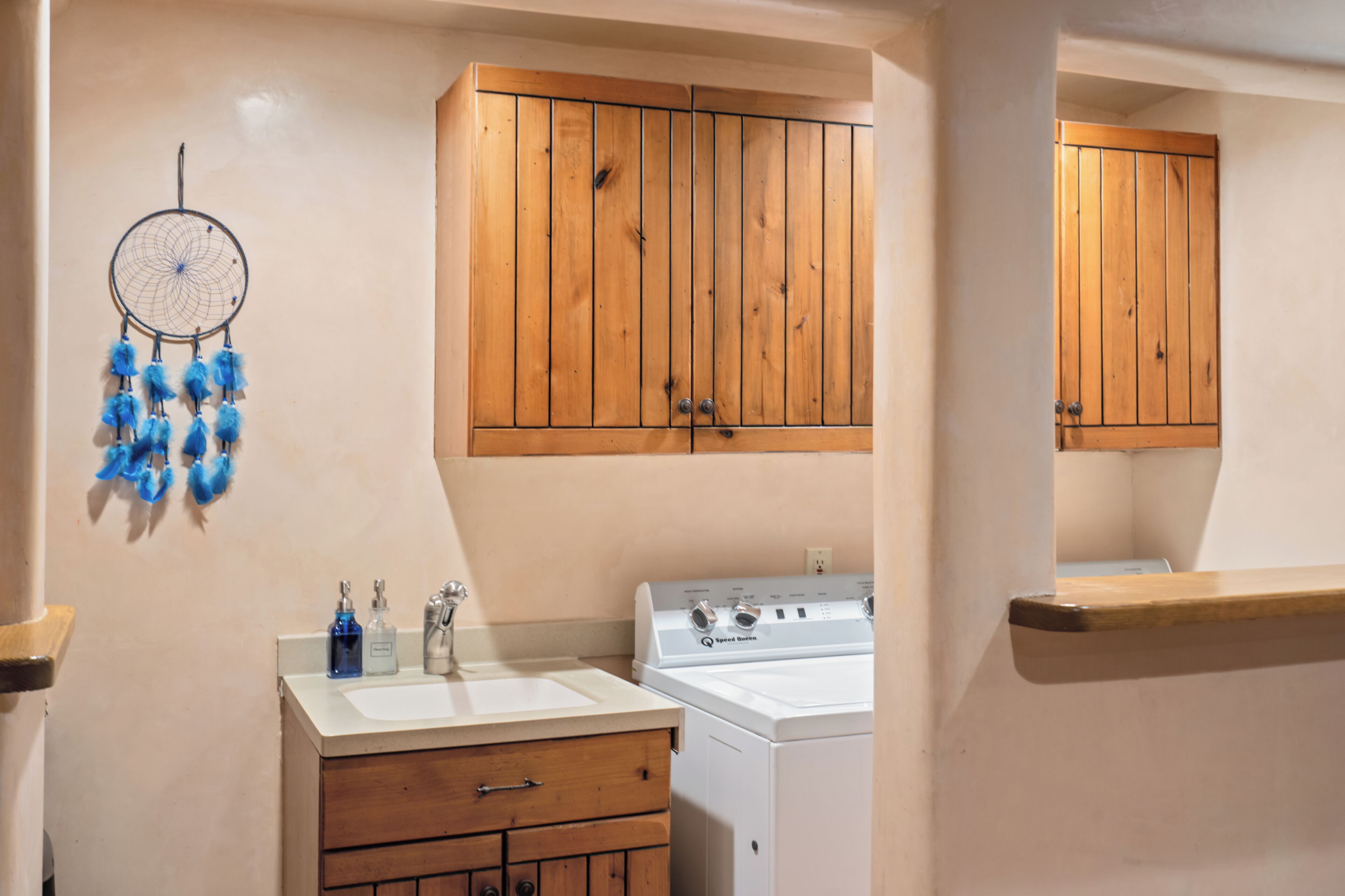 A kitchen with wooden cabinets, a white stove, and a dreamcatcher on the wall.