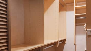 Un armario abierto con repisas de madera, una barra para colgar ropa y una silla.