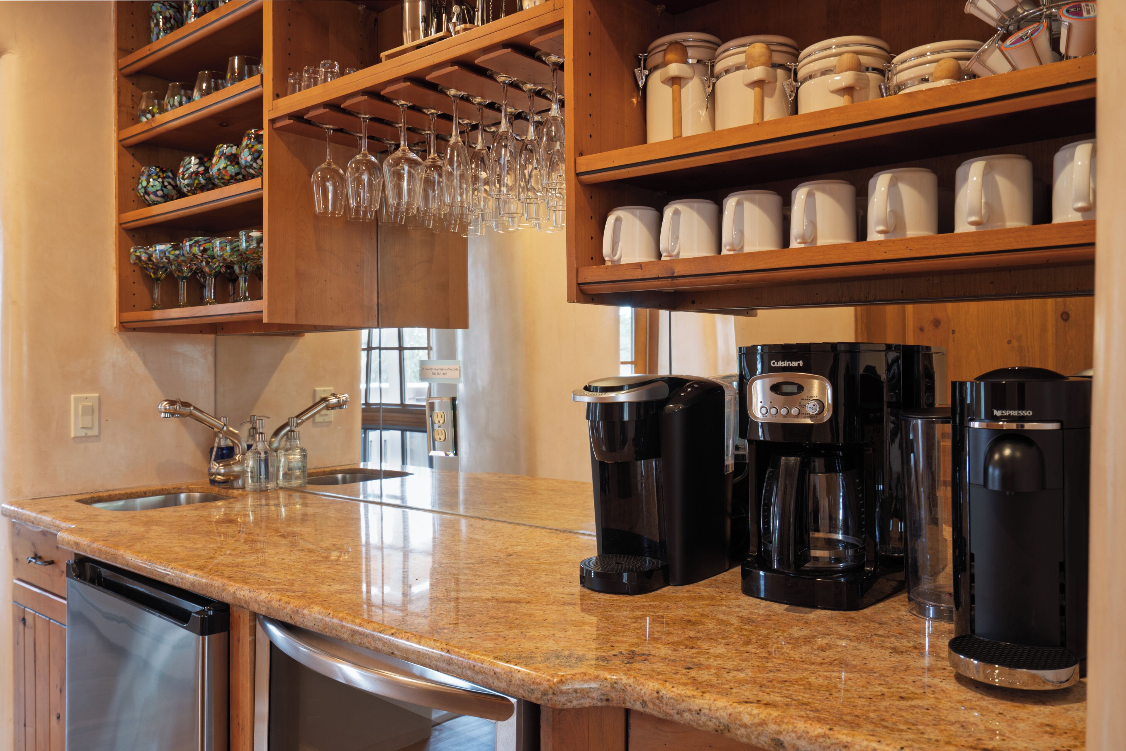 Una cocina con encimera de granito, cafeteras y lavavajillas.