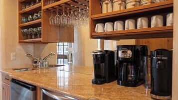 Una cocina con encimera de granito, cafeteras y lavavajillas.