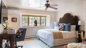 Un dormitorio con cama, ventilador de techo, ventana con vistas y escritorio con planta.