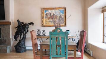 A dining area with a wooden table, chairs, a painting on the wall, and a statue.