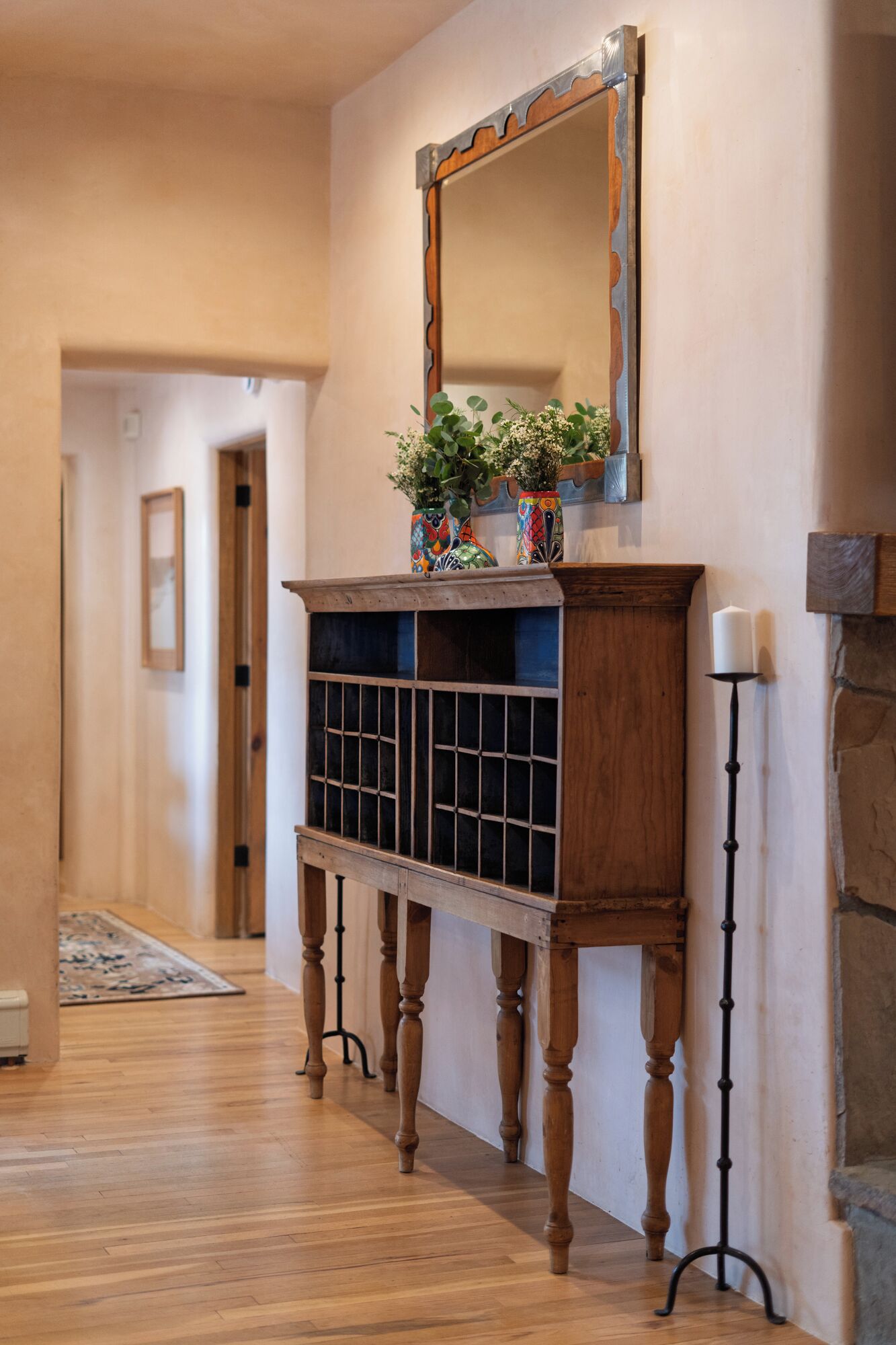 A hallway with a wooden console table, a mirror, and a candle holder.