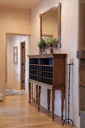 Un couloir avec une console en bois, un miroir et un chandelier.