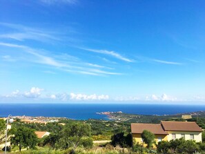 A coastal landscape with a clear view of the sea and distant buildings. - Affittimoderni Isola Rossa Élite (Trinità d'Agultu e Vignola)