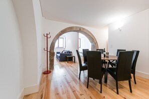 Enjoy meals in this dining area with a round table and six chairs, adjacent to a cozy living space with a sofa and coffee table.