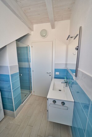 A bathroom with a shower, a sink, and a mirror. - Affittimoderni Isola Rossa Borgo (Trinità d'Agultu e Vignola)