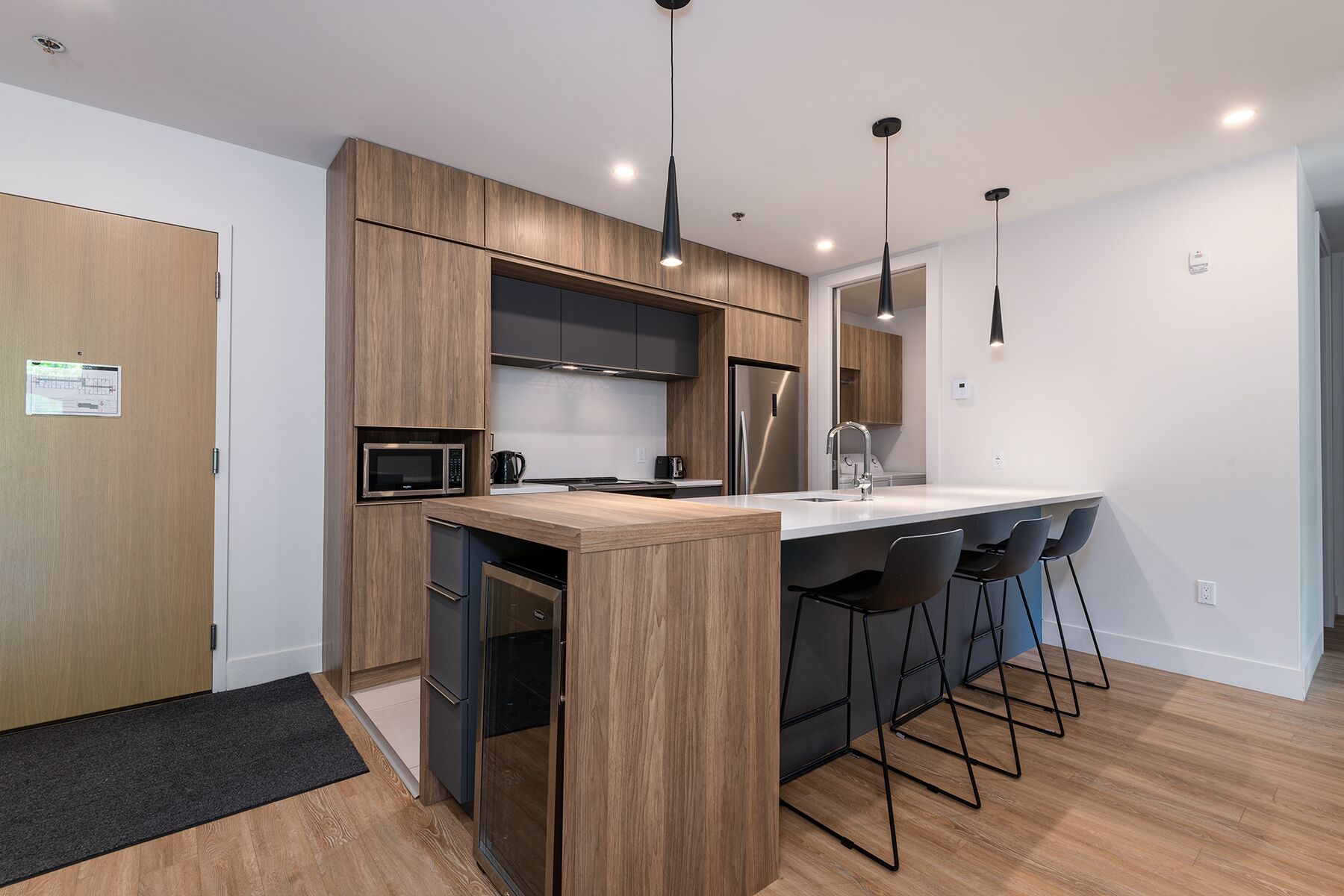 A modern kitchen with wooden cabinetry, stainless steel appliances, and a bar area with stools.
