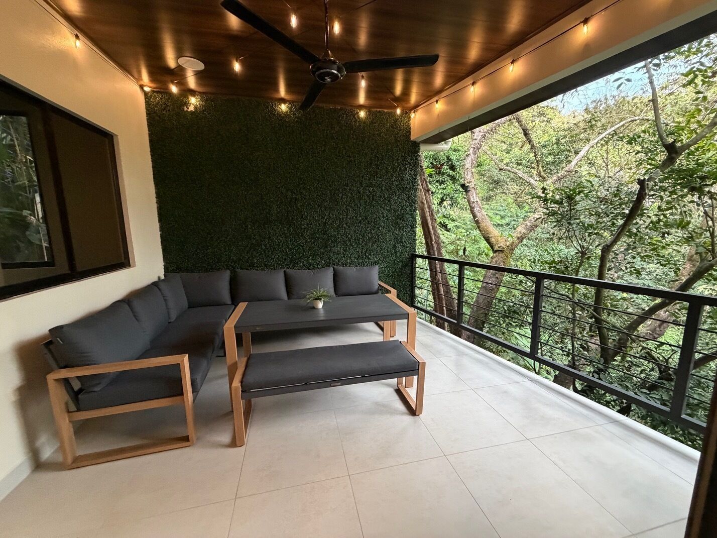 Un balcon agrémenté d’un mur végétal, d’un banc en bois et d’un canapé.