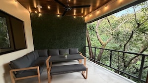 Un balcone con parete verde, una panca di legno e un divano.