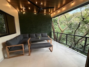 A balcony with a green wall, a wooden bench, and a sofa.