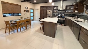 Una cucina moderna con pensili in legno scuro, un'isola centrale e una zona pranzo con sedie in legno.