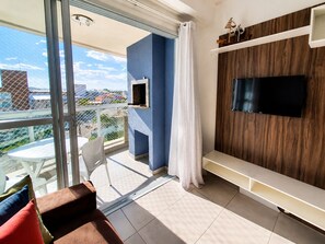 Un balcon avec une porte vitrée, une table blanche et un canapé rouge et marron.