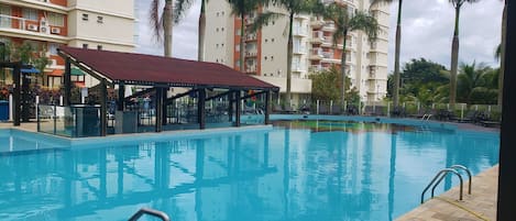 Una piscina al aire libre, sombrillas, sillones reclinables de piscina
