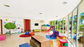 Un espace de jeux pour enfants avec un toboggan, des tentes et des sièges colorés.