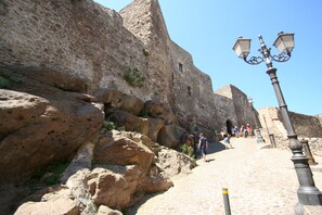 A stone pathway leading up a rocky hill with a lamp post and a signpost.