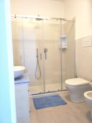 A modern bathroom with a glass-enclosed shower, a white toilet, and a sink.