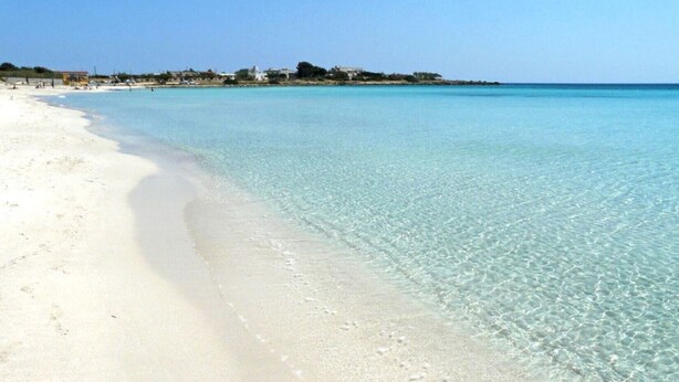 Ein Strand mit klarem türkisblauem Wasser und weißem Sand.