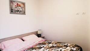 Ein Schlafzimmer mit einem Bett, einem Nachttisch, einer Lampe und einem gerahmten Bild an der Wand.