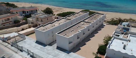 Un edificio moderno con techo plano y varios balcones, junto a la playa.