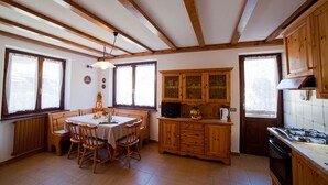 A kitchen with wooden cabinets, a dining table with chairs, and a stove. - TWO-ROOM RELAX SPA SKI AND TREKKING IN THE ALPS (Santa Caterina)