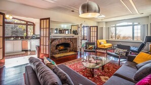A spacious living room with a fireplace, a dining area, and large windows. - Stunning View, Frank Lloyd Wright Inspired Home (Salt Lake City)