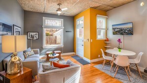 A living room with a sofa, coffee table, and a dining area with a table and chairs. - New distinctive historical  unit from 5 Star Host (Salt Lake City)