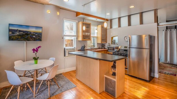 A modern kitchen with a central island, stainless steel appliances, and a dining area with a round table and chairs. - New distinctive historical  unit from 5 Star Host (Salt Lake City)