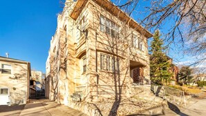 Ein historisches Steinhaus mit einer markanten Eingangspforte, einem kleinen Balkon und einer Treppe zum Eingang.