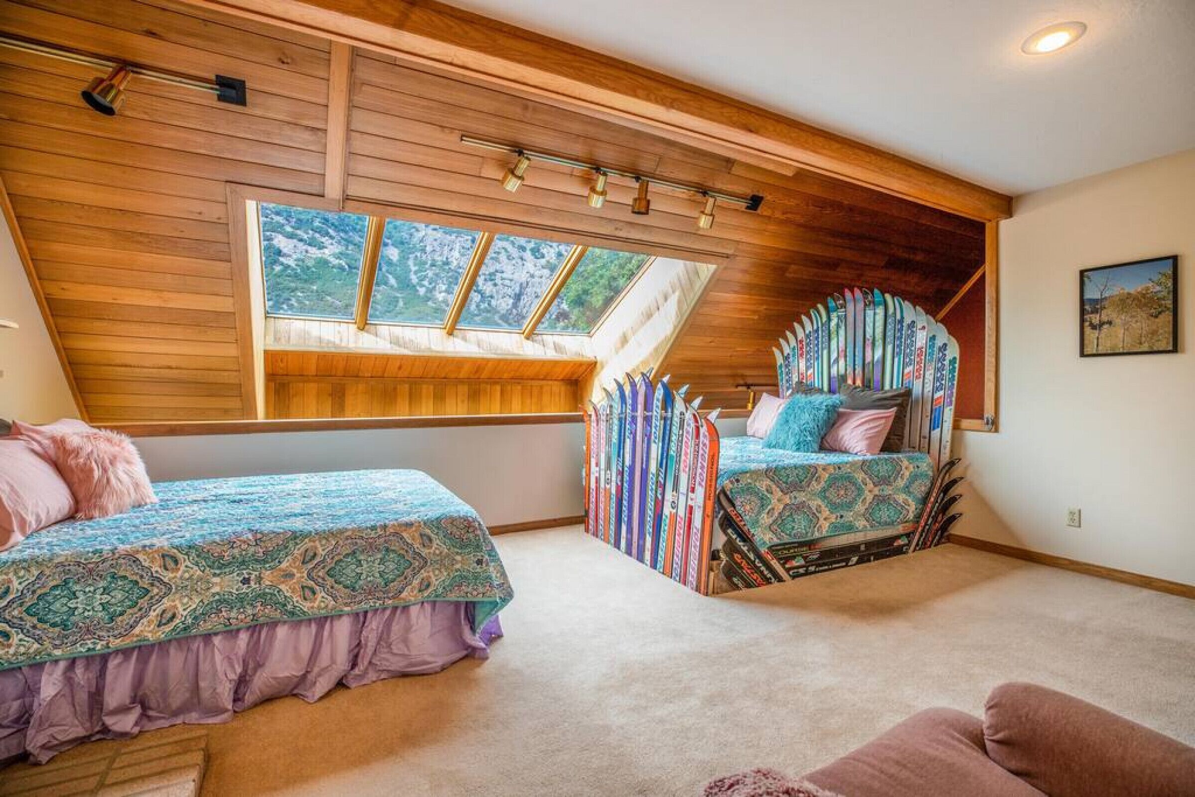 Ein Schlafzimmer mit zwei Betten, einem Dachfenster und einer Sammlung von Surfbrettern an der Wand.