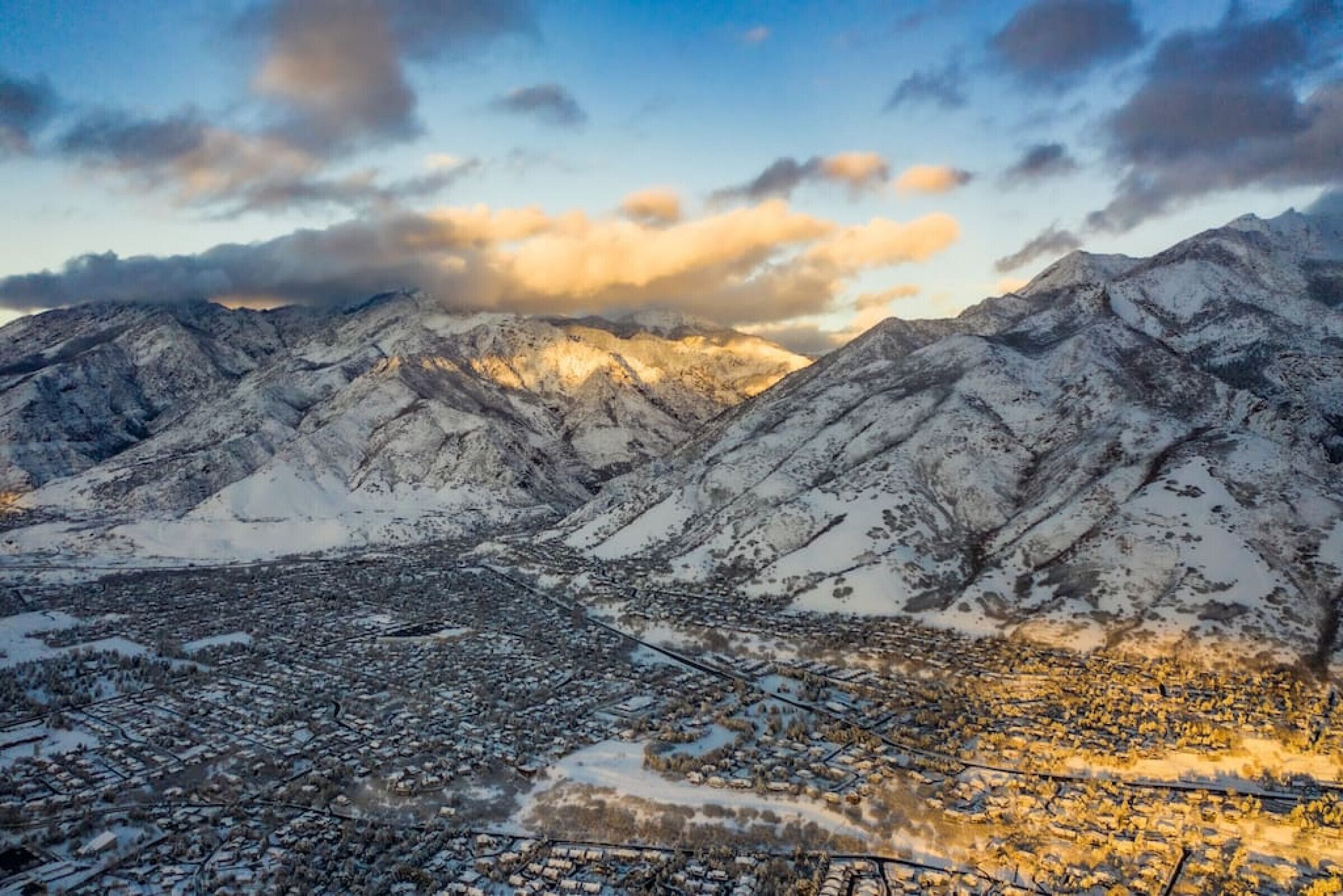 A panoramic view of a snow-covered mountainous region with a town in the foreground.