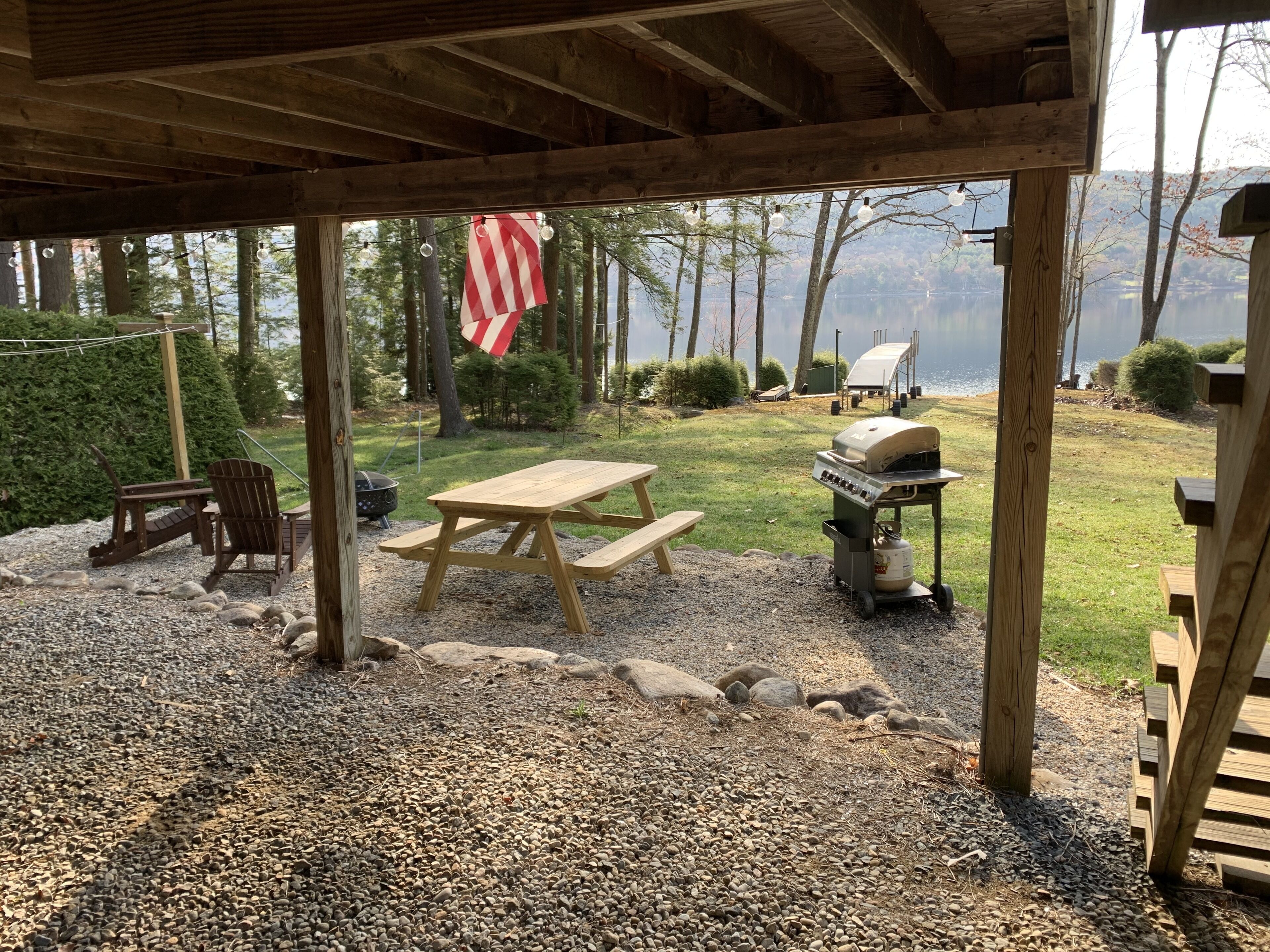 A covered outdoor area with a picnic table, grill, and seating.