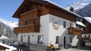 Un bâtiment en bois à plusieurs étages, doté de balcons, d'un télésiège et surplombant un paysage montagneux.
