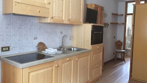 A kitchen with wooden cabinets, a stainless steel sink, and a built-in oven. - MOUNTAIN HOLIDAYS 4 SAISON SANTA CATERINA VALFURVA (Santa Caterina)