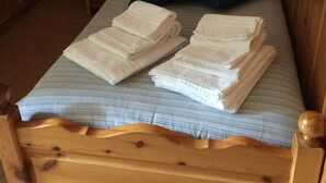 A wooden bed with a striped mattress, two pillows, and folded towels. - MOUNTAIN HOLIDAYS 4 SAISON SANTA CATERINA VALFURVA (Santa Caterina)