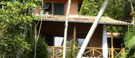 A two-story building with a balcony, surrounded by trees.