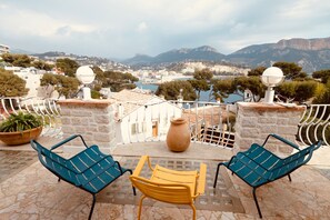 Une terrasse avec deux chaises, une table et un grand vase.