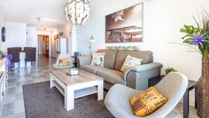 Ein modernes Wohnzimmer mit Sofa, Sessel, Couchtisch und einer Pendelleuchte.