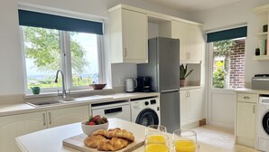 Une cuisine moderne équipée d’un lave-linge et d’un sèche-linge intégrés, d’une machine à café et offrant une vue sur l’extérieur.