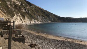 Une plage rocheuse offrant une vue dégagée sur la mer et bordée d’une falaise abrupte.