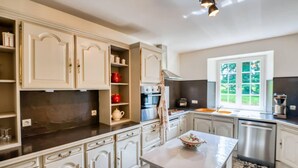 A modern kitchen with white cabinetry, a large window, and a stainless steel dishwasher. - Cottages, bed and breakfasts in the heart of the North Finistère countryside. (Finistère)