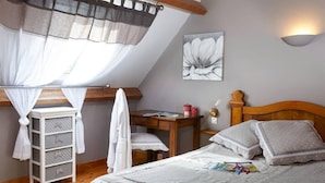 A bedroom with a bed, a desk, a chair, a wardrobe, and a window with a curtain. - Cottages, bed and breakfasts in the heart of the North Finistère countryside. (Finistère)