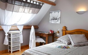 Ein Schlafzimmer mit Bett, Schreibtisch, Stuhl, Kleiderschrank und einem Fenster mit Vorhang.