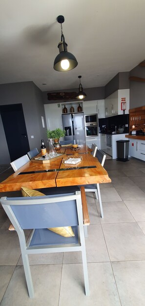 A modern kitchen with white cabinets, a stainless steel refrigerator, and a wooden dining table with chairs.