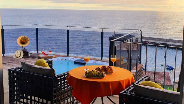 Terras met een zwembad, een tafel met eten en drinken, en uitzicht op de zee.