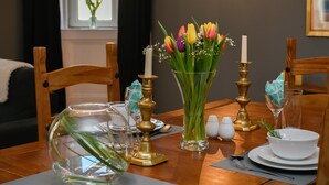Une table à manger dressée avec un vase de tulipes, des bougies et des salières et poivrières.