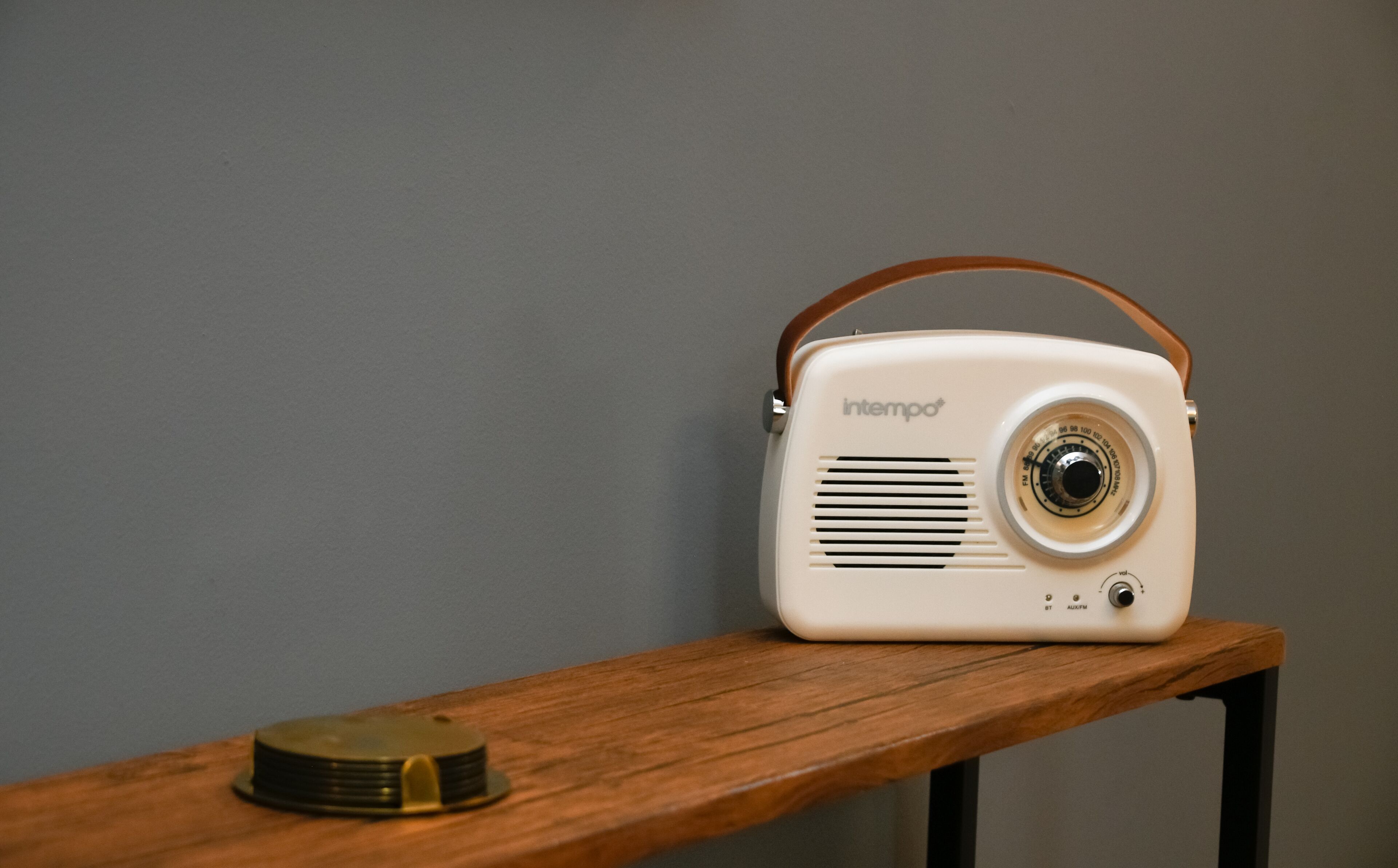 A vintage radio with a handle on a wooden shelf.