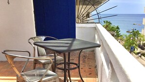 A balcony with a table and chairs, overlooking the sea.